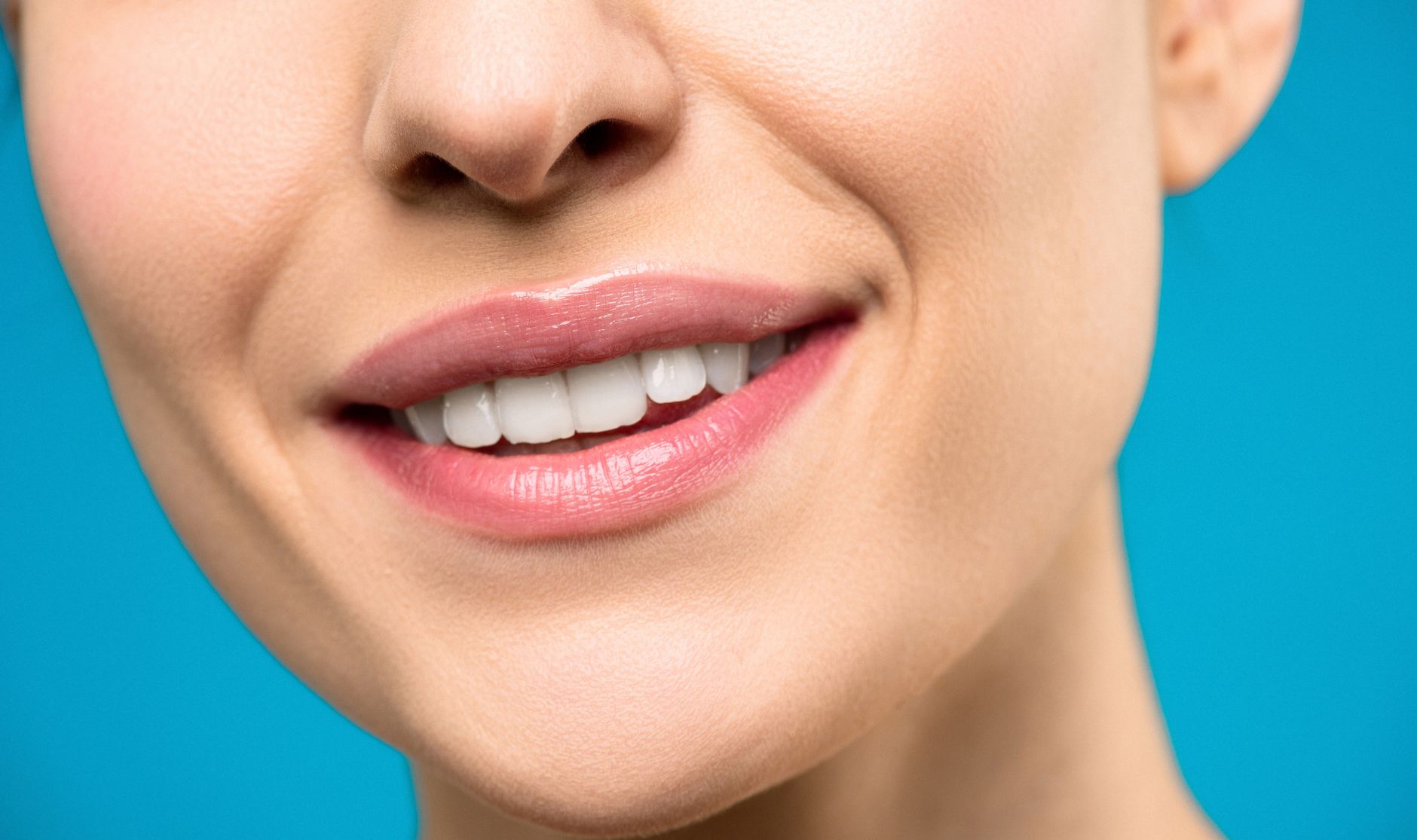 A close-up image of a woman's smile with pink lipstick and w מי מטפל בשיניים שלך - ד